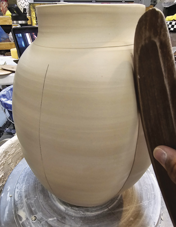 10 Use a long wooden rib to press the clay at each of the vertical divider lines.