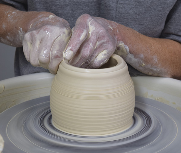 1 Using 2–3 lbs (0.9–1.4 kg) of clay, open up a short and wide cylinder with a flat floor ¼ in. (0.6 cm) thick. Pull the walls up and begin to taper inward.