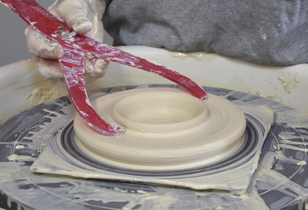 7 Pull out from the center, building up a ring of clay to fit inside the feeder top. Measure the ring with the first set of calipers.