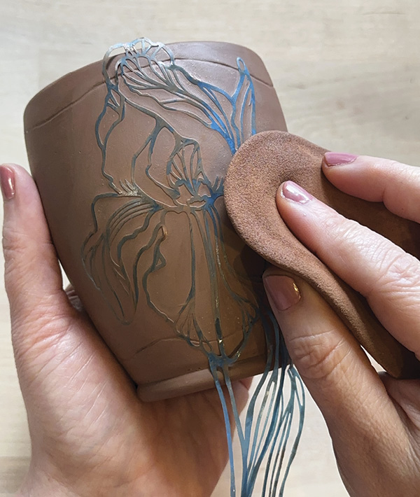 1 Gently wipe a soft, damp sponge over the stencil to adhere it to the exterior clay surface.