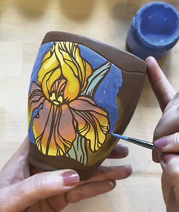 13 Add 3 coats of underglaze to the negative space around the stenciled design to connect the front and back of the vessel.