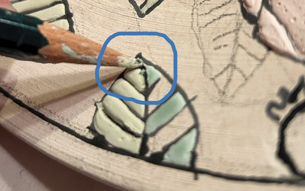 8 If glaze flows over a wax line (top), use a pencil tip to scrape it off (bottom).