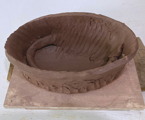 5 Once leather hard, attach a soft coil to the interior join, working it into the walls and floor to create a continuous curve.