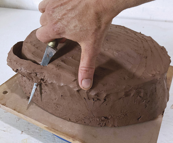 7 Flip the server upside down onto a board, and use a knife to remove the ledge of excess clay to create a continuous dome.