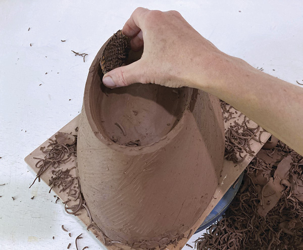 10 Use a Surform to roughly shape the outer profile and inside of the foot, while removing excess clay. Level the foot.