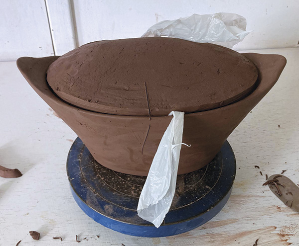 14 Using a Surform, remove clay from the edges to fit the lid to the pot. Using a strip of plastic to remove the lid as needed.