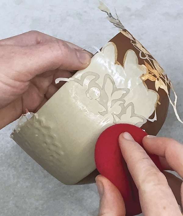 7 Apply negative-space newsprint stencils, then apply two coats of white slip.