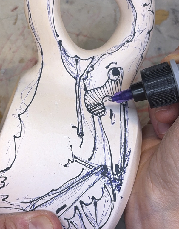 3 Using a squeeze bottle, trace all the pen lines with black underglaze.