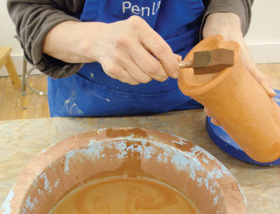 Applying terra sigillata to foot of the bone dry pot.