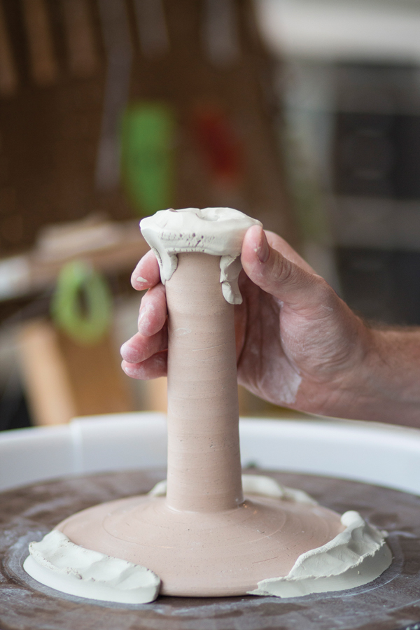 1 Center and stick the saturated, bisque-fired chuck to the wheel head with clay, then and add another coil of clay at the top.
