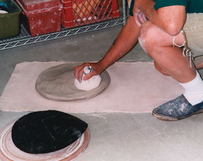 Use the pounding pad to flatten a block of clay into a round slab as shown here. This slab will be used to throw a large platter.