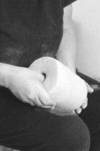 A cylindrical ball of clay is opened with the thumb. Using up to an 8-pound ball of clay for a pinchpot has become second nature.