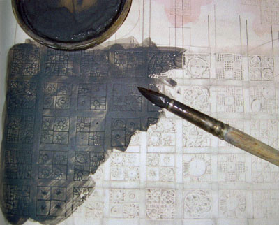 2. Black casting slip is painted over the surface. When the slip has dried to leatherhard, the excess is scraped away with a metal kidney, leaving the design showing as black lines.