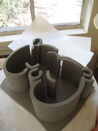 A sculpture of the letter E in progress (shown face down), with leather-hard side-wall slabs shown placed on the front slab.
