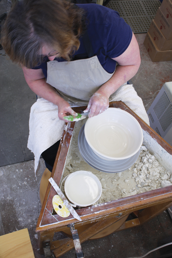 2 Finishing the shape and rim of a bowl thrown on a treadle wheel. Using a large stiff rubber rib removes throwing marks.