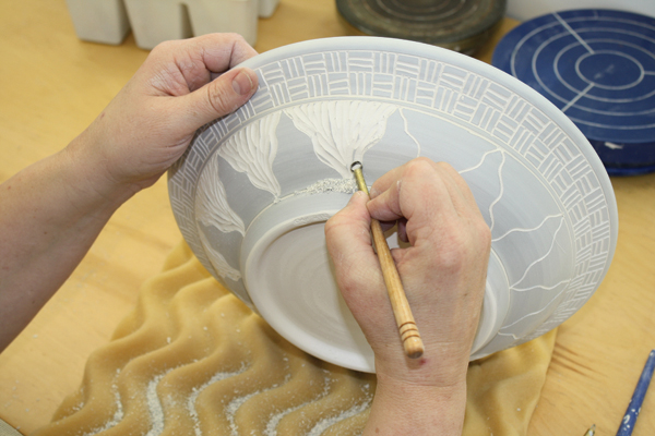 5 After defining the outlines, remove slip from the negative spaces using larger loop trimming and carving tools.