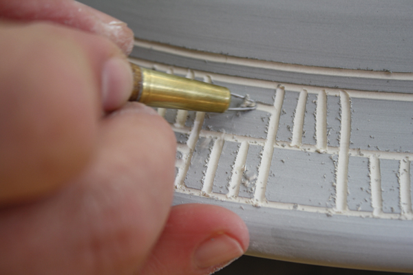 8 Carving linear patterns around the rim of a bowl that reference a field of crops planted in rows.