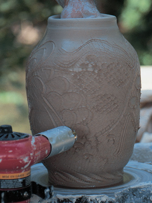 Expand the soft, decorated form on the wheel from the inside, while drying with a heat gun on the outside.