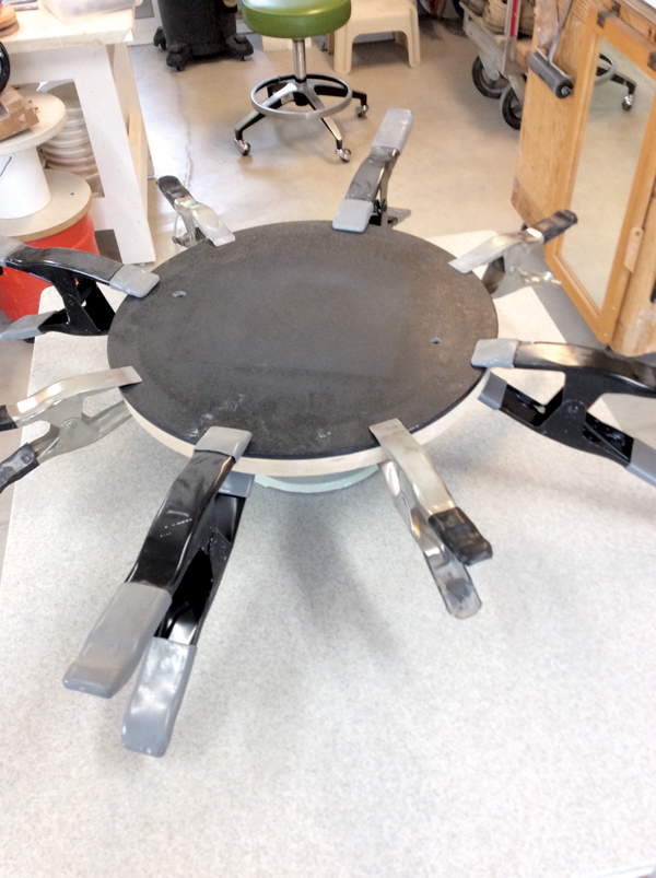 4 Take the bat out of the boiling water and immediately clamp it to the wooden bat on top of the two CDs. 