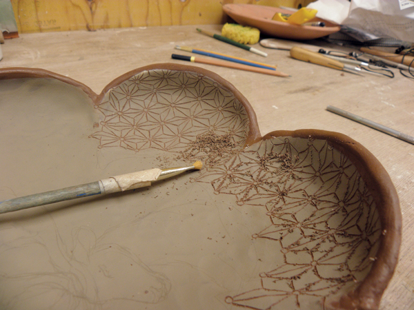 A Use a sharp needle tool to carve in the pattern before carving or painting any other details.