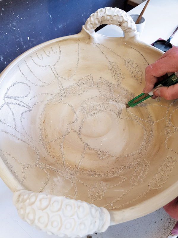 8 Apply a coat of wax resist to the interior, then draw freehand designs through the wax and slip with a sharp knife.