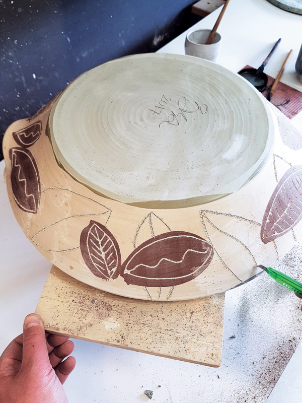 10 Apply wax to the exterior, add sgraffito details to the black shapes, and carve additional design elements on the exterior.