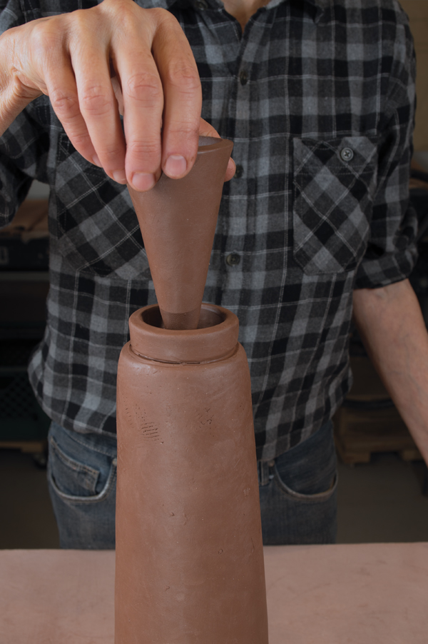 13 Test fit the cone by placing it into the opening on the bottle. Cut off the excess height using a strip of plastic as a guide.