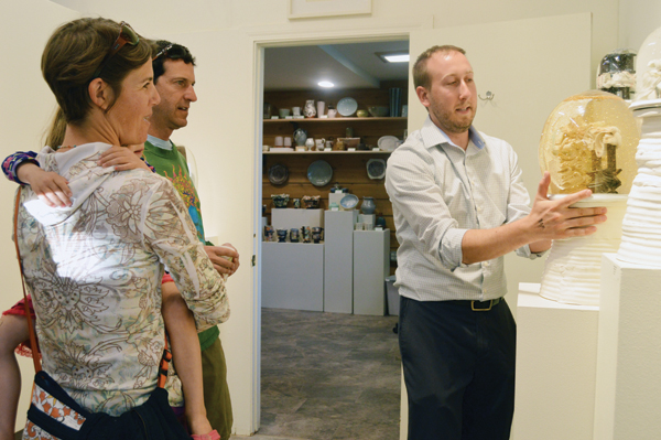 1 Carbondale Clay Center Studio Manager and ceramic artist Matthew Eames demonstrates one of his ceramic snow globes at the opening reception of his June solo exhibit, “Threw & Thru.” The piece he is holding is Tumescent V, 20 in. (51 cm), ceramics, glass and glitter, fired to cone 1, 2017. Photo: Jessica Cabe.