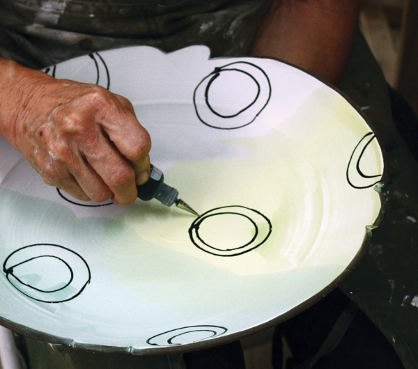 1 Apply color to the whole surface on a bisque-fired piece, then apply black underglaze outlines with a small applicator bottle fitted with a metal tip.