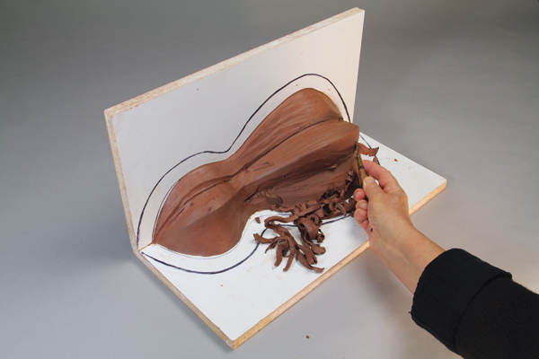 3 If you want a faceted, fluted, or carved surface, begin carving the solid clay form with a trimming tool. Other options: leave it smooth, stamp texture, or add basrelief elements.