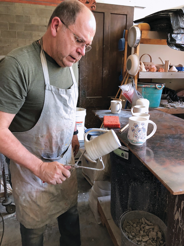 1 Potter Phil Sellers applies glaze at River Hill Pottery, North Adams.