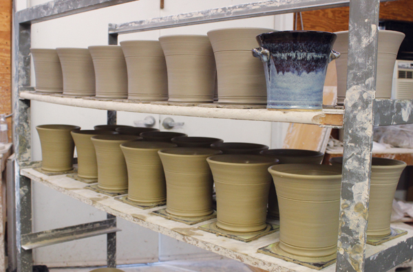 6 Shelves of leather-hard beer-bread bakers next to a finished baker at Great White Oak Gallery in Seagrove.