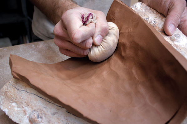 5 Pound the clay into the crevices with a sandbag to evenly distribute it.