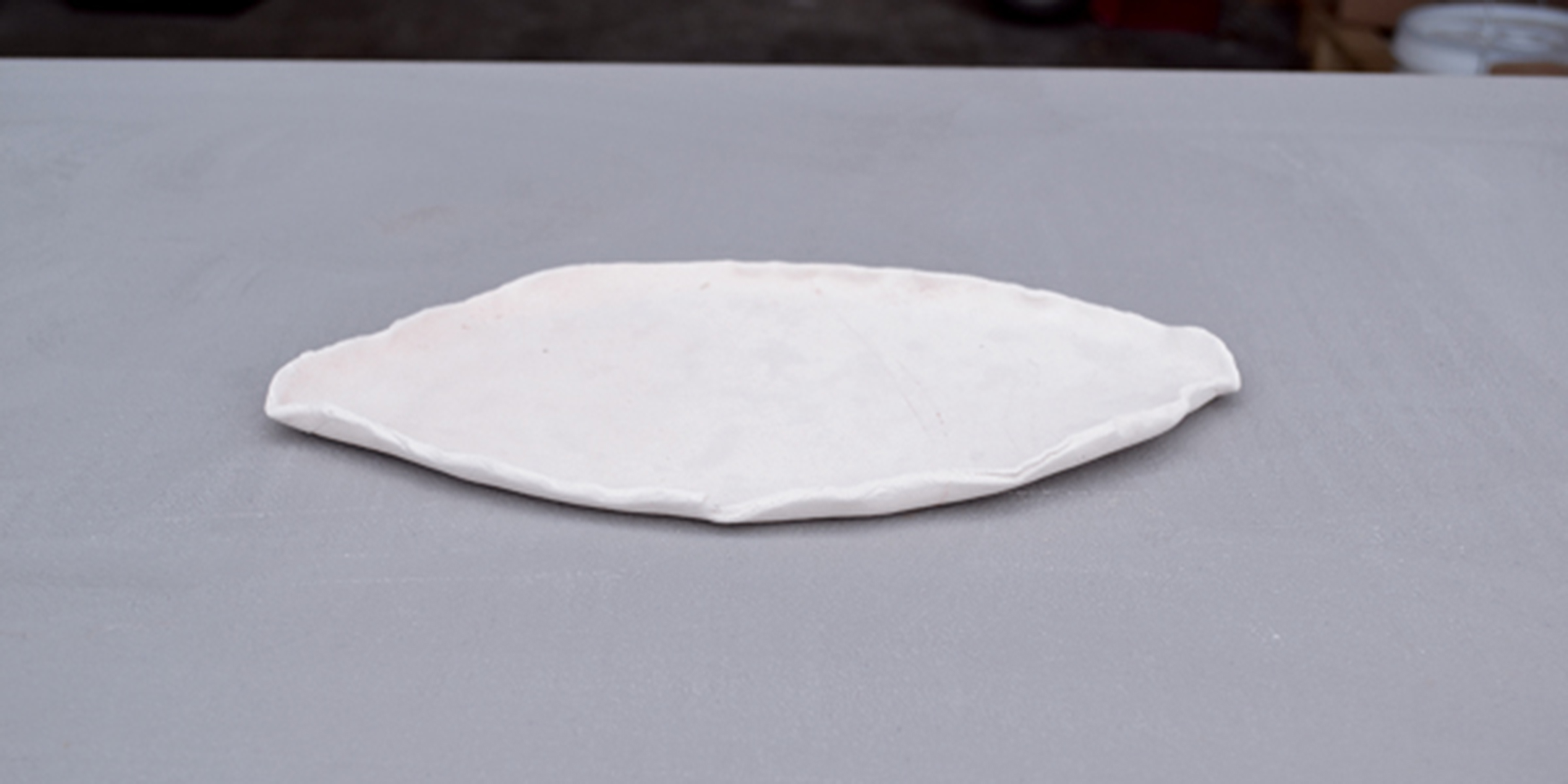 3 Roll out a slab that is slightly larger than your pot to use as a waster slab, which will catch any possible glaze drips. Curl up the edges of the tray to catch any pooling glazes. Bisque fire your drip tray.