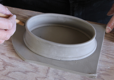 9 Take the leather-hard, flat slab of clay and trace the outline of the bottom of the lid.