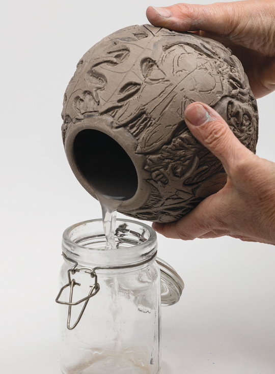4 Clean up dried carving crumbs then pour water into and out of the leather-hard pot to keep moisture content consistent.