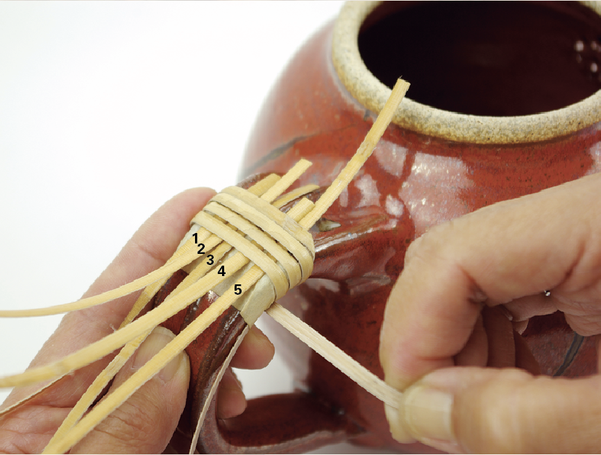 2 Tightly wrap the cane about ½ inch above the masking tape. Wrap 4 times around the handle. Insert 5 strands of binder cane under the wrap, so that they protrude beyond the wrapping.