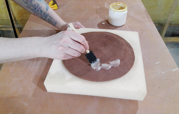 10 Brushing wax on the foot when the plate is leather hard.