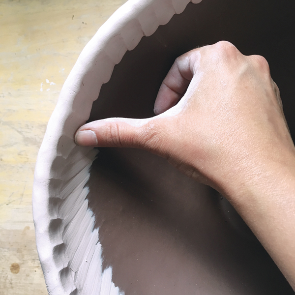 5 Smooth the contrasting clay down the interior of the piece while supporting the form on the exterior to prevent distortion.