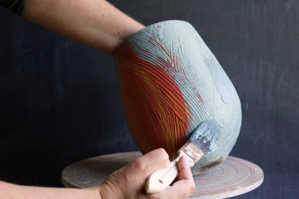 9 Continue to add broad strokes of the darker blue slip to add texture and depth.
