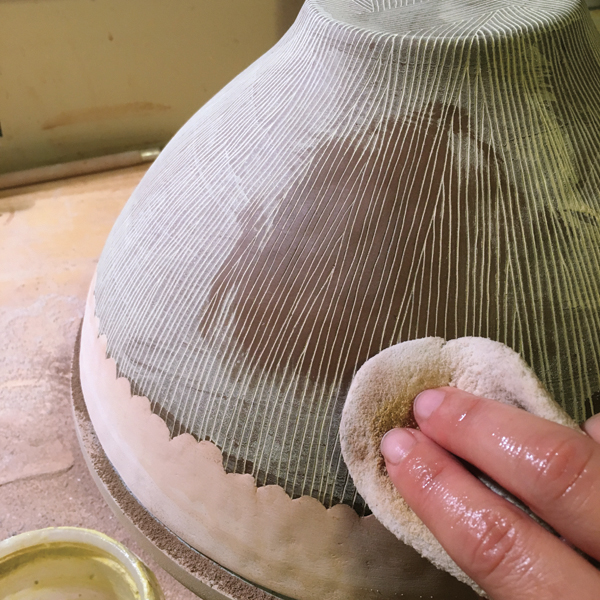 13 Wipe the residue of slip off of the waxed surface with a damp sponge, allowing slip to remain in the carved lines.