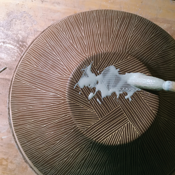 14 Paint an additional color of slip into the signature scratched into the rewaxed bottom.