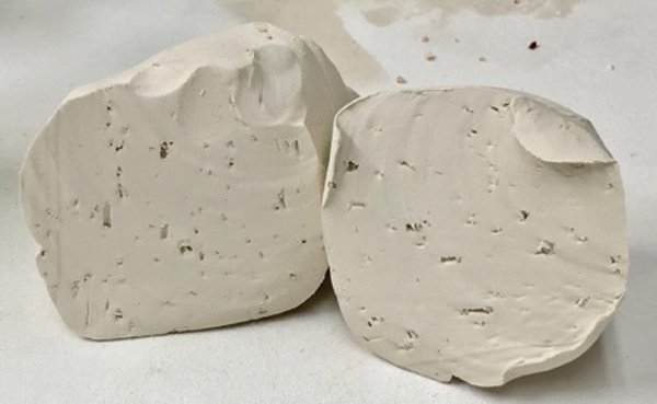 2 Wedge the feldspar and molochite inclusions into your clay body. Cut the wedged ball in half to make sure the inclusions are evenly dispersed.