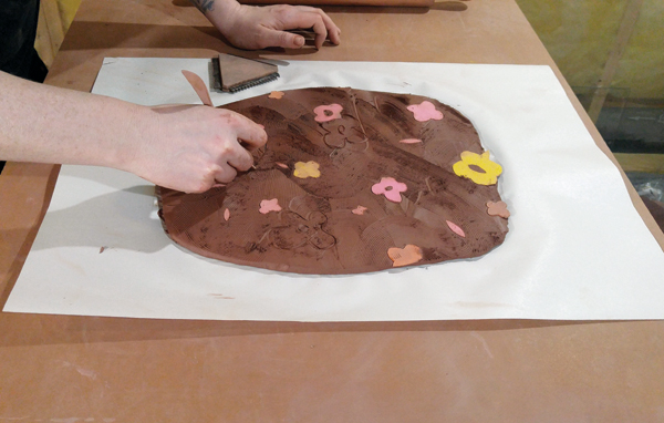 3 Drawing designs into the clay using a pointed wooden tool.