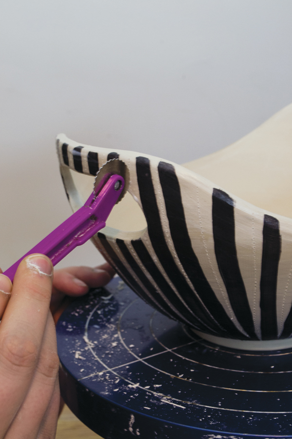8 After the wax is no longer sticky, roll a stitch roller in between the stripes to impress stitch marks.