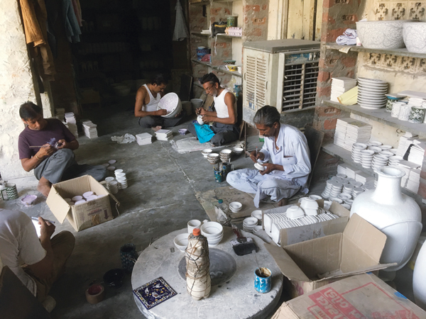 8 Decorating is the most time-consuming part of production. Workers sit on the floor in the dark to escape the mid-day heat while working.