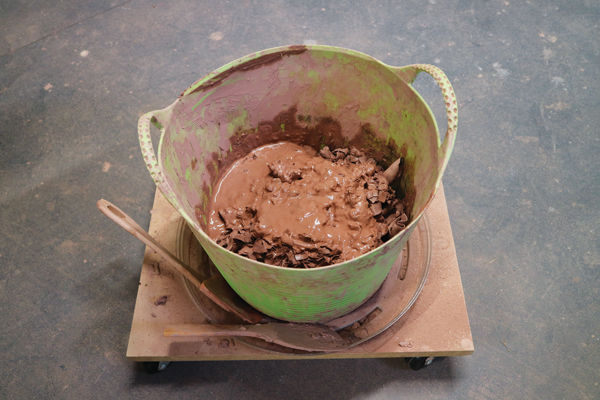 2 Leather-hard trimmings, plus throwing water and its sludge, are added to the bucket.