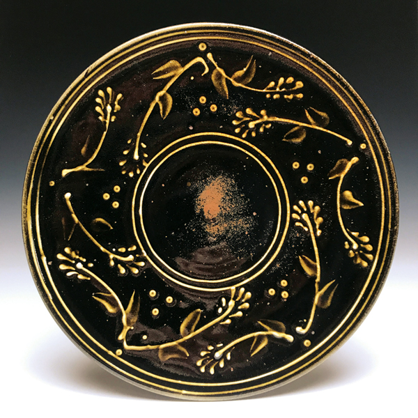 6 Dinner plate, 11 in. (28 cm) in diameter, red stoneware, white slip-trailed decoration, tenmoku glaze, soda fired to cone 11 in a gas kiln, 2017.