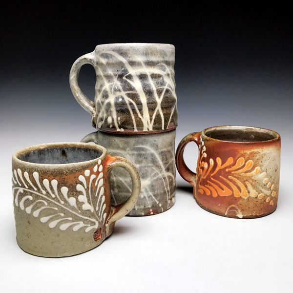 2 Mugs, 6 in. (15 cm) in width, red stoneware, nuka glaze, flashing slip, white slip-trailed decorations, soda fired to cone 11 in a gas kiln, 2018.