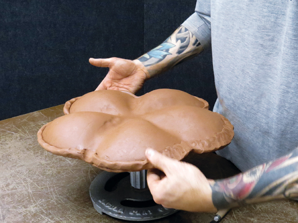 6 Compress the slab against the bisque mold, trim the edge of the slab to the edge of the mold, and add a coil to the rim.